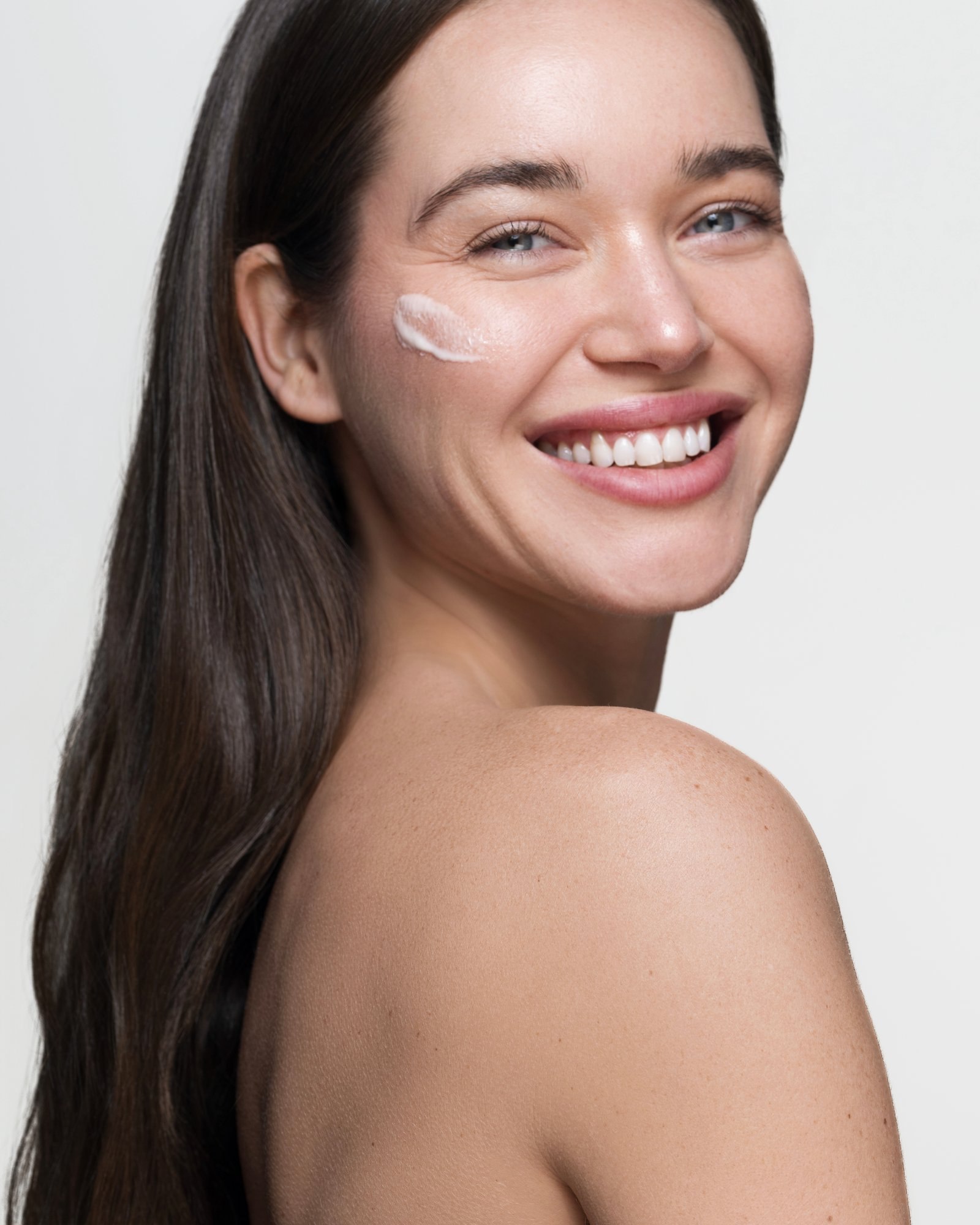Skincare product, applying cream to cheek