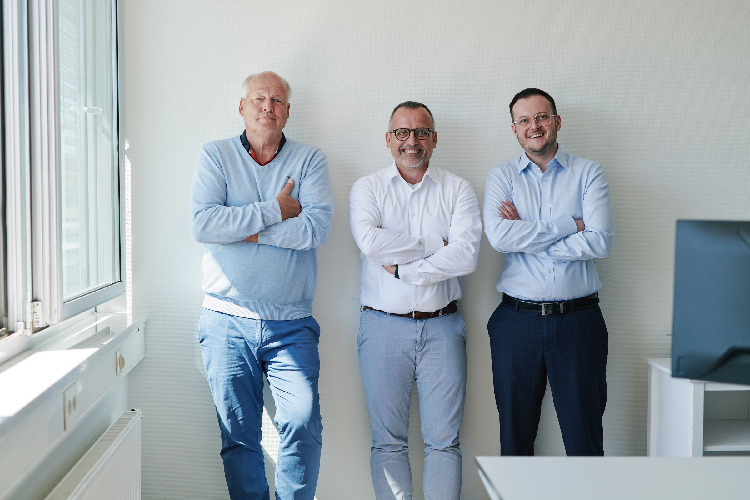 Team portrait, three colleagues against a wall