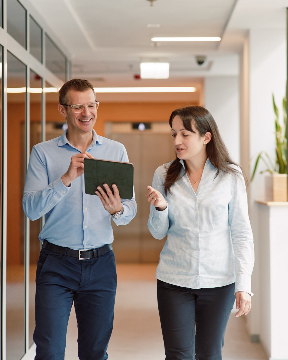 Colleagues walking a hallway with a tablet