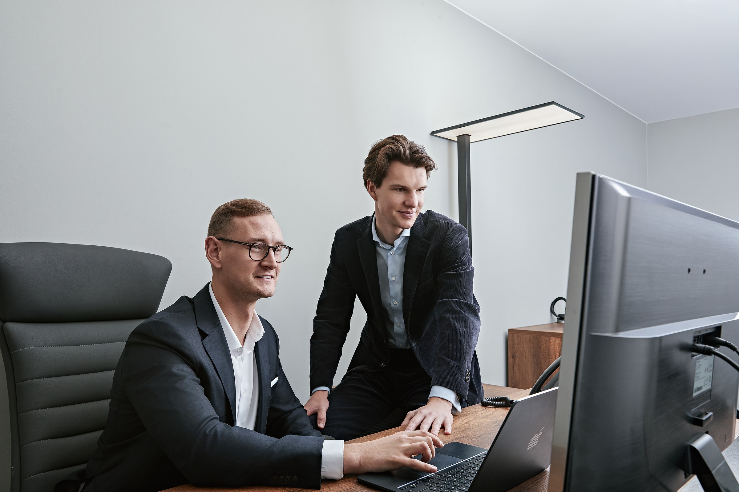 Two colleagues reviewing a laptop at a desk