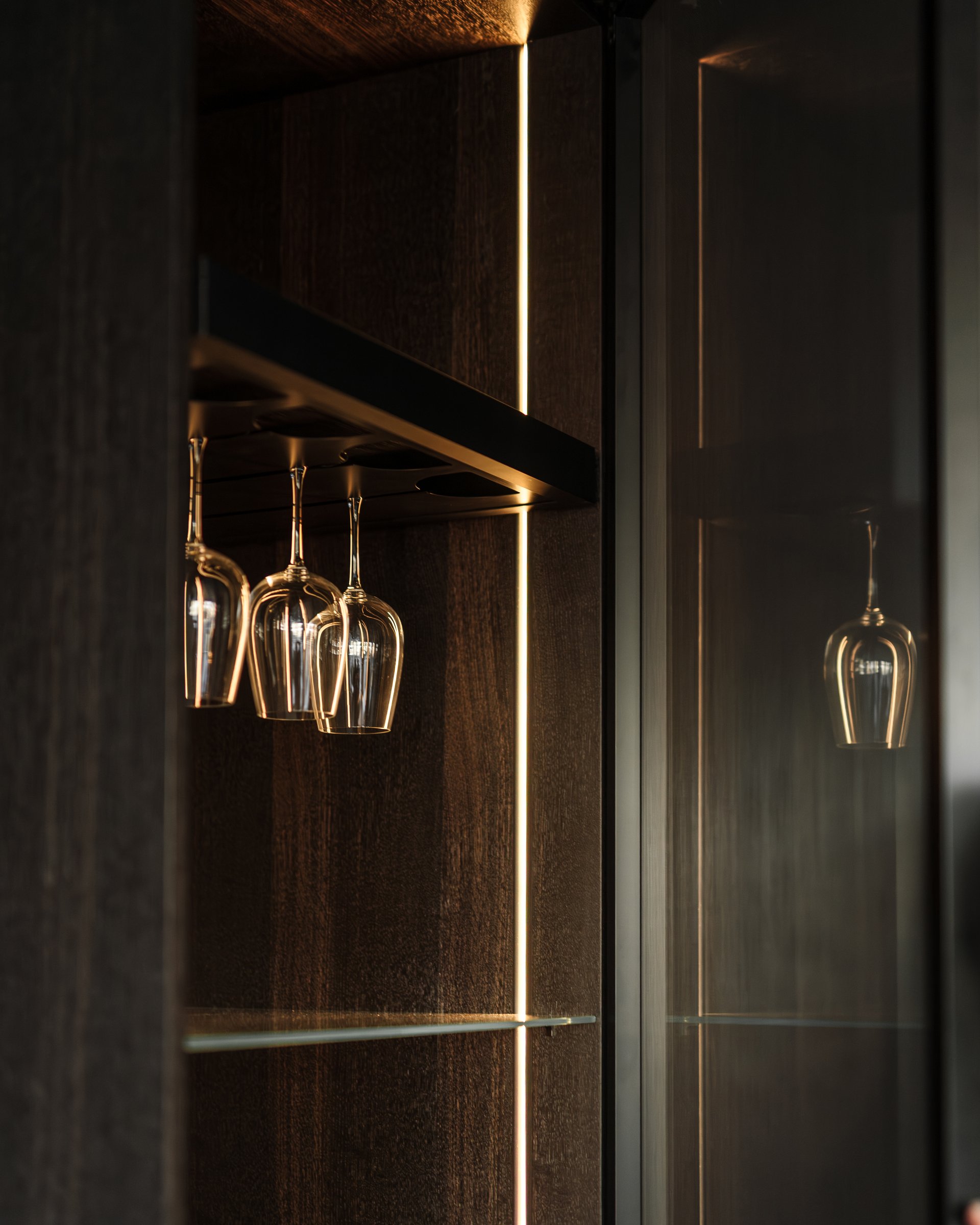 Dark apartment, wine glasses in backlit cabinet