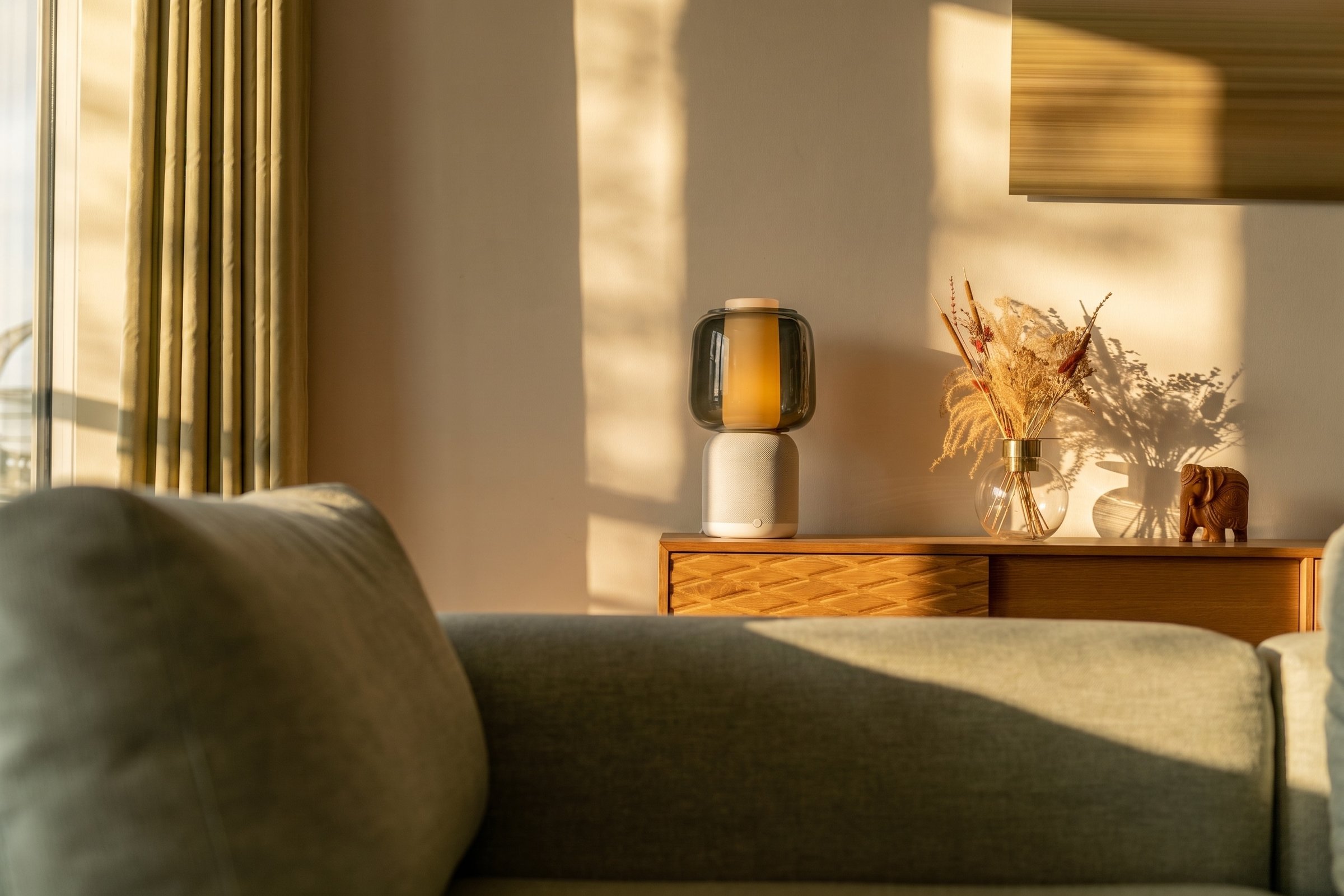 Sunlit apartment, table lamp and dried flowers on a credenza