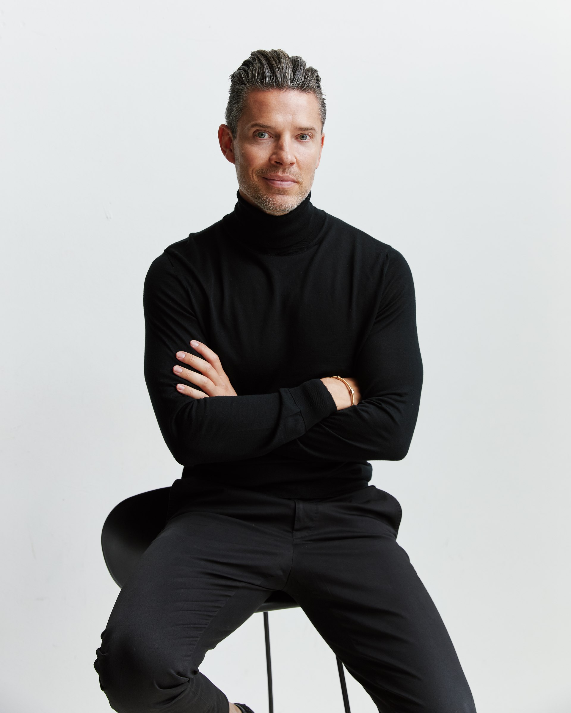 Studio portrait, seated, black turtleneck, arms crossed